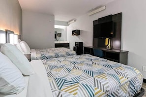 Habitación de hotel con dos camas, un escritorio, una silla, un televisor de pantalla plana y un espejo.