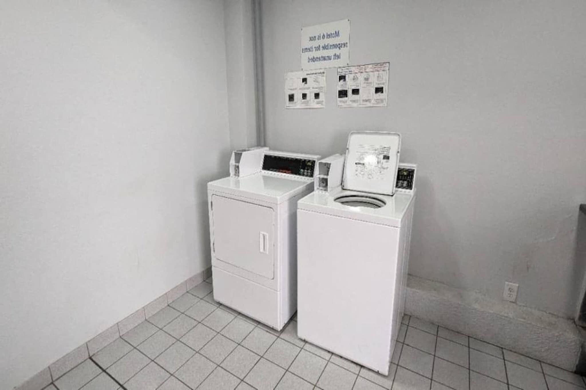 Une buanderie avec deux machines à laver blanches et une pancarte au-dessus.