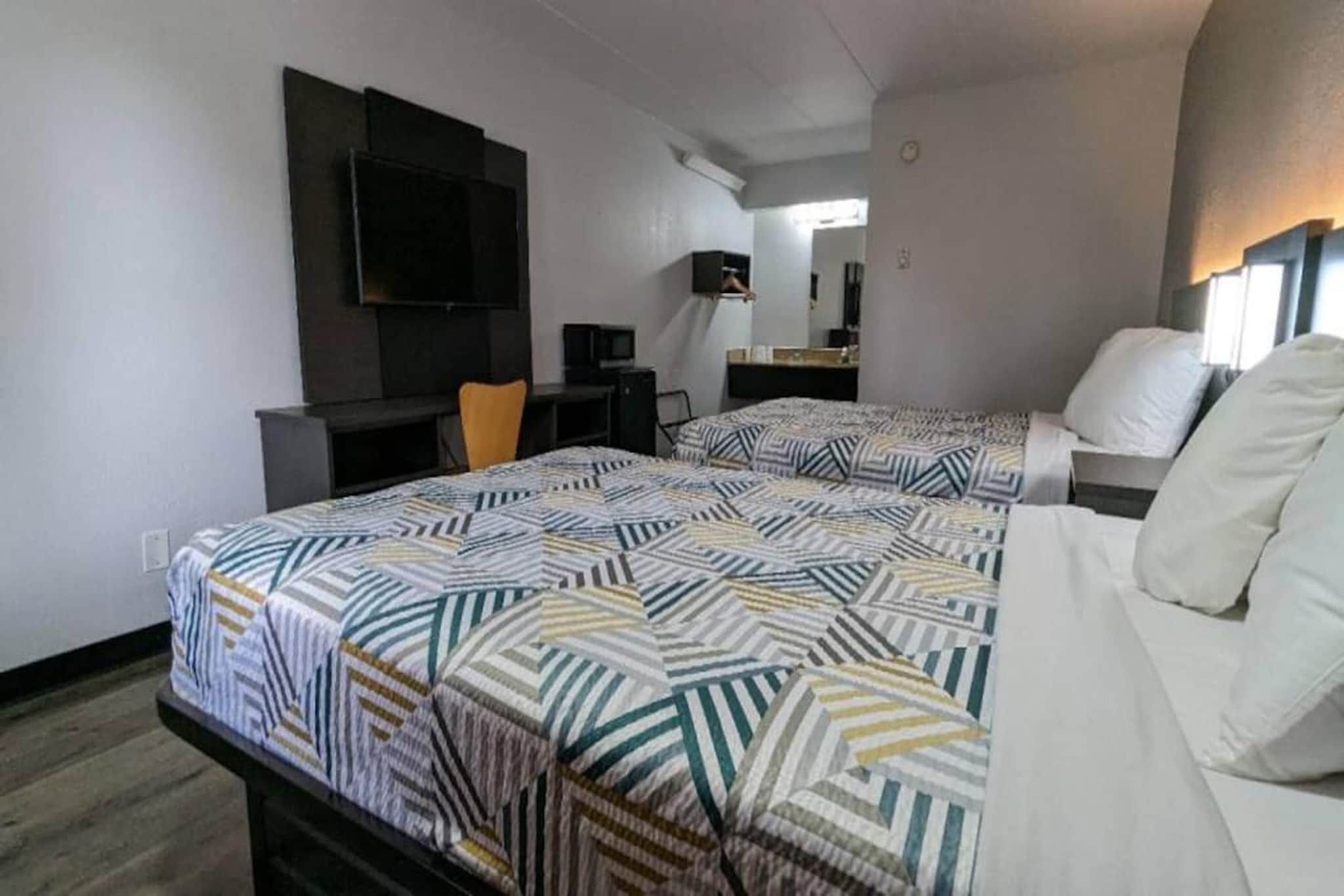 Une chambre d’hôtel avec deux lits, une télévision, un bureau et une chaise.