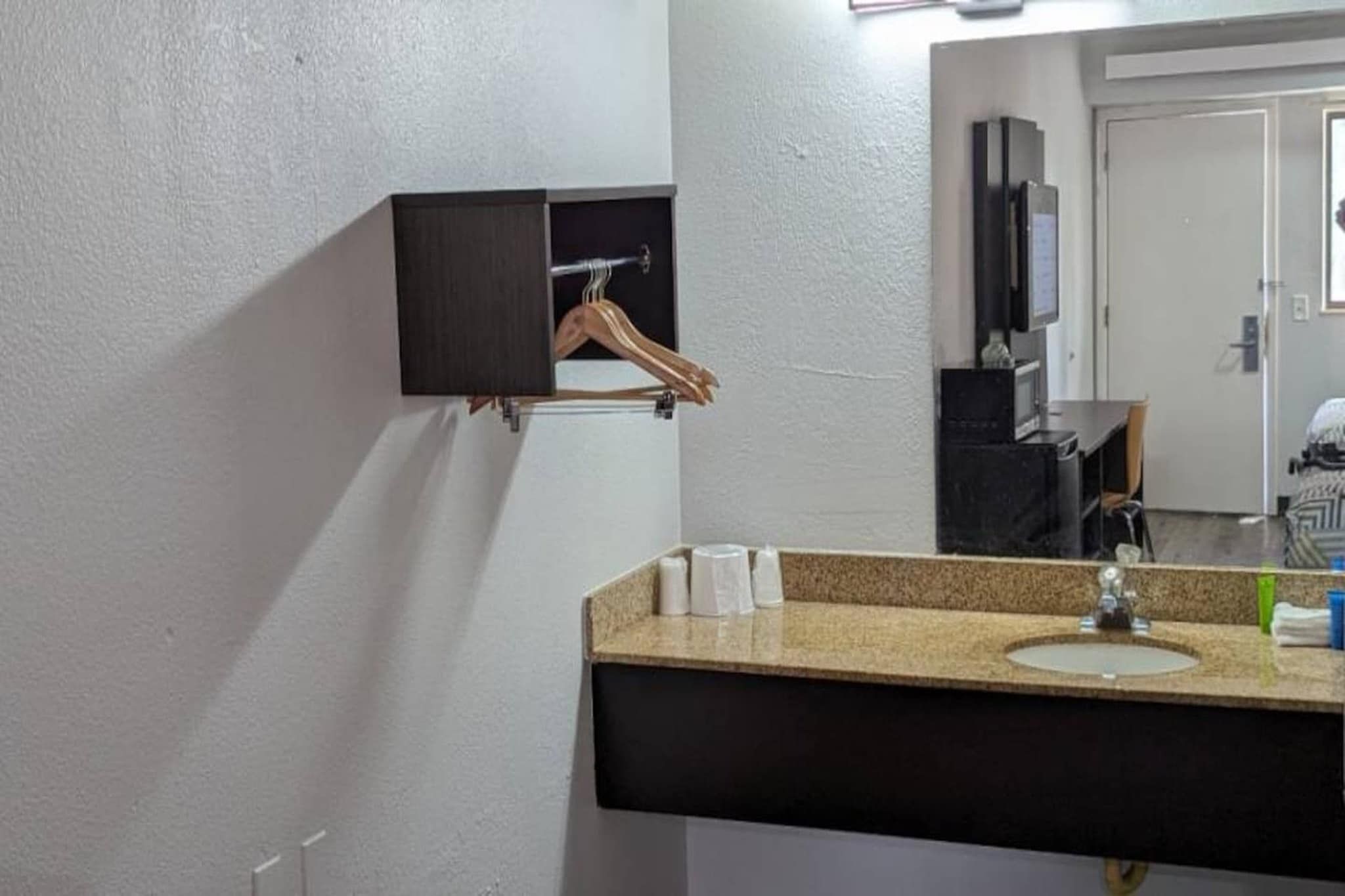 A bathroom with a sink, mirror, towel rack, and a cabinet with a hanging towel.