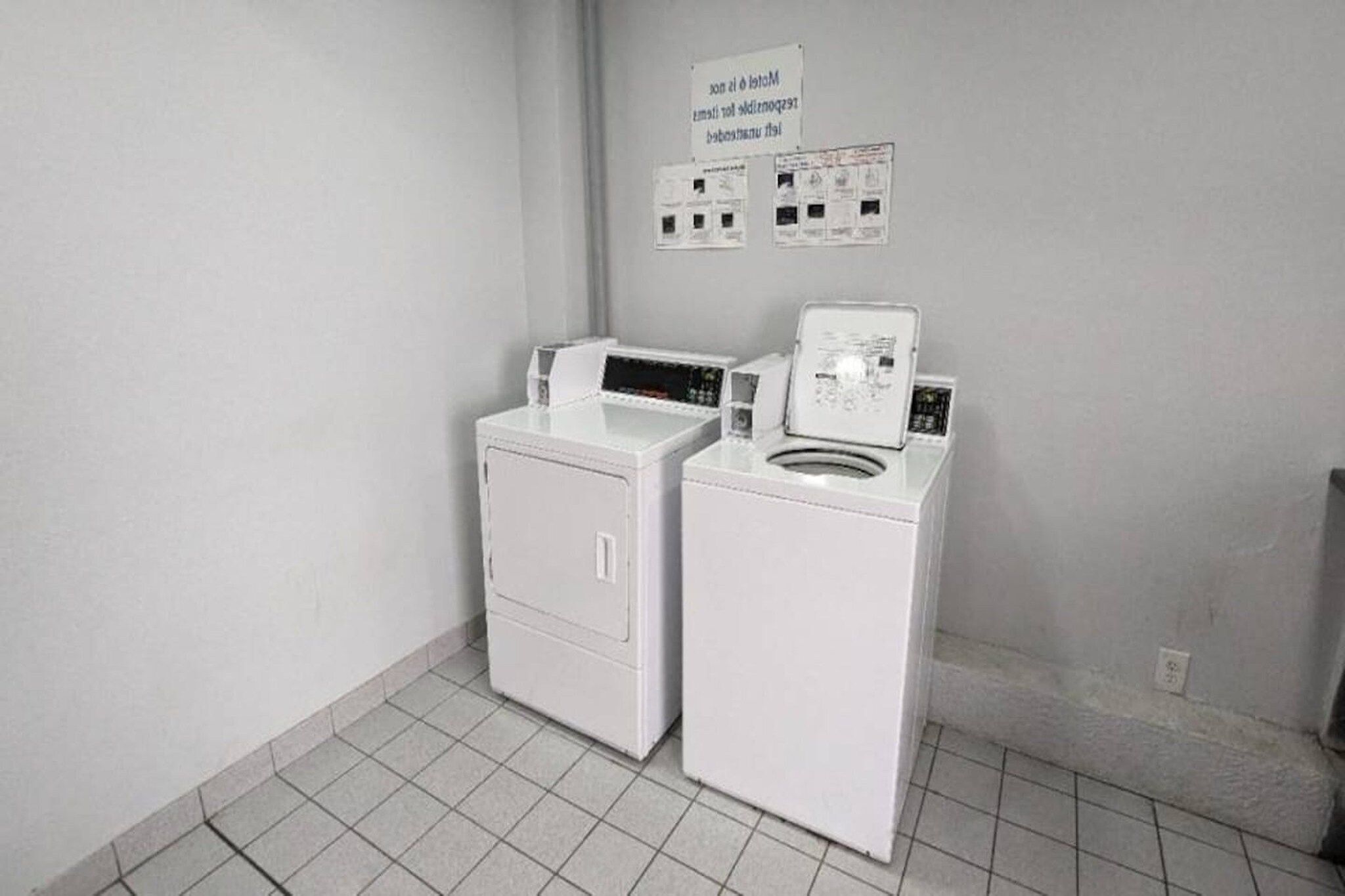Een wasserette met twee witte wasmachines en een bord erboven.