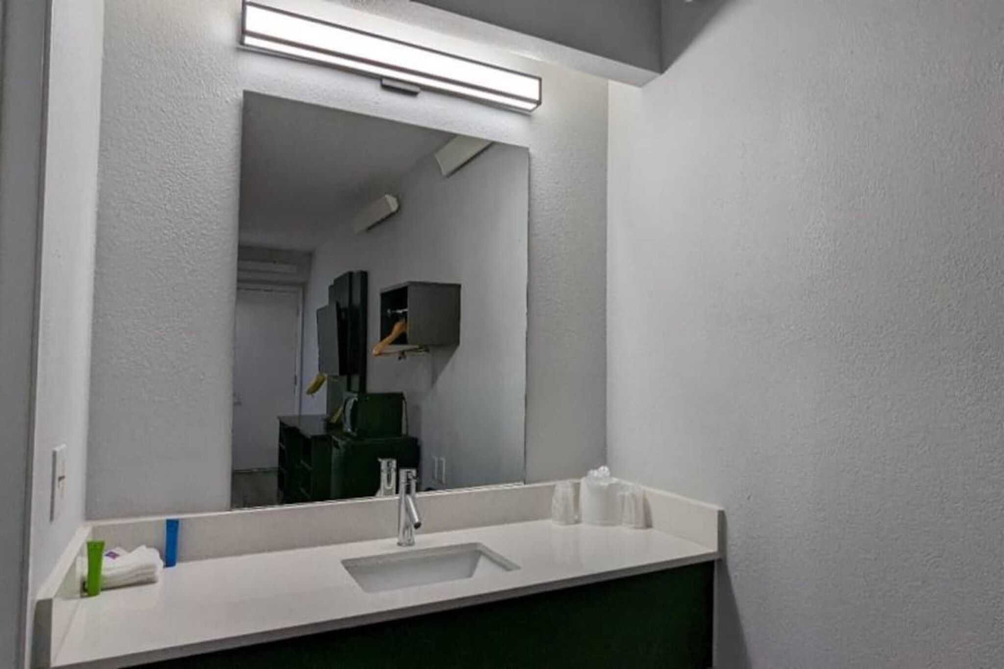 A bathroom with a white sink, a mirror, and a green cabinet.