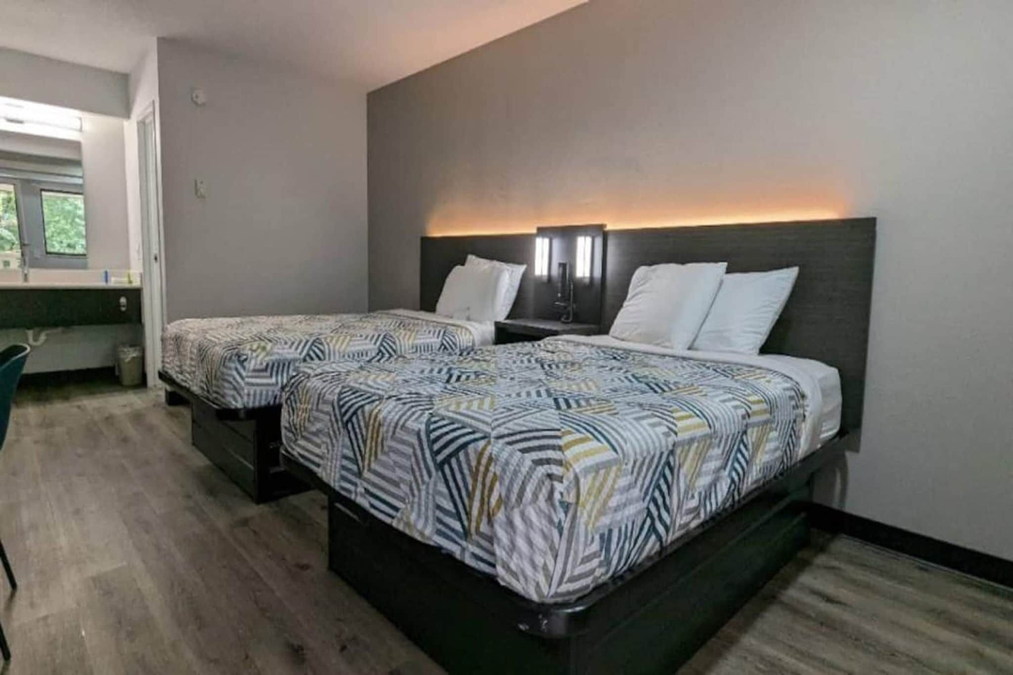 A hotel room with two beds, a desk, and a chair.