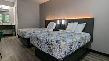 A hotel room with two beds, a desk, and a chair.