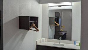 Un baño con lavamanos blanco, espejo y perchero.