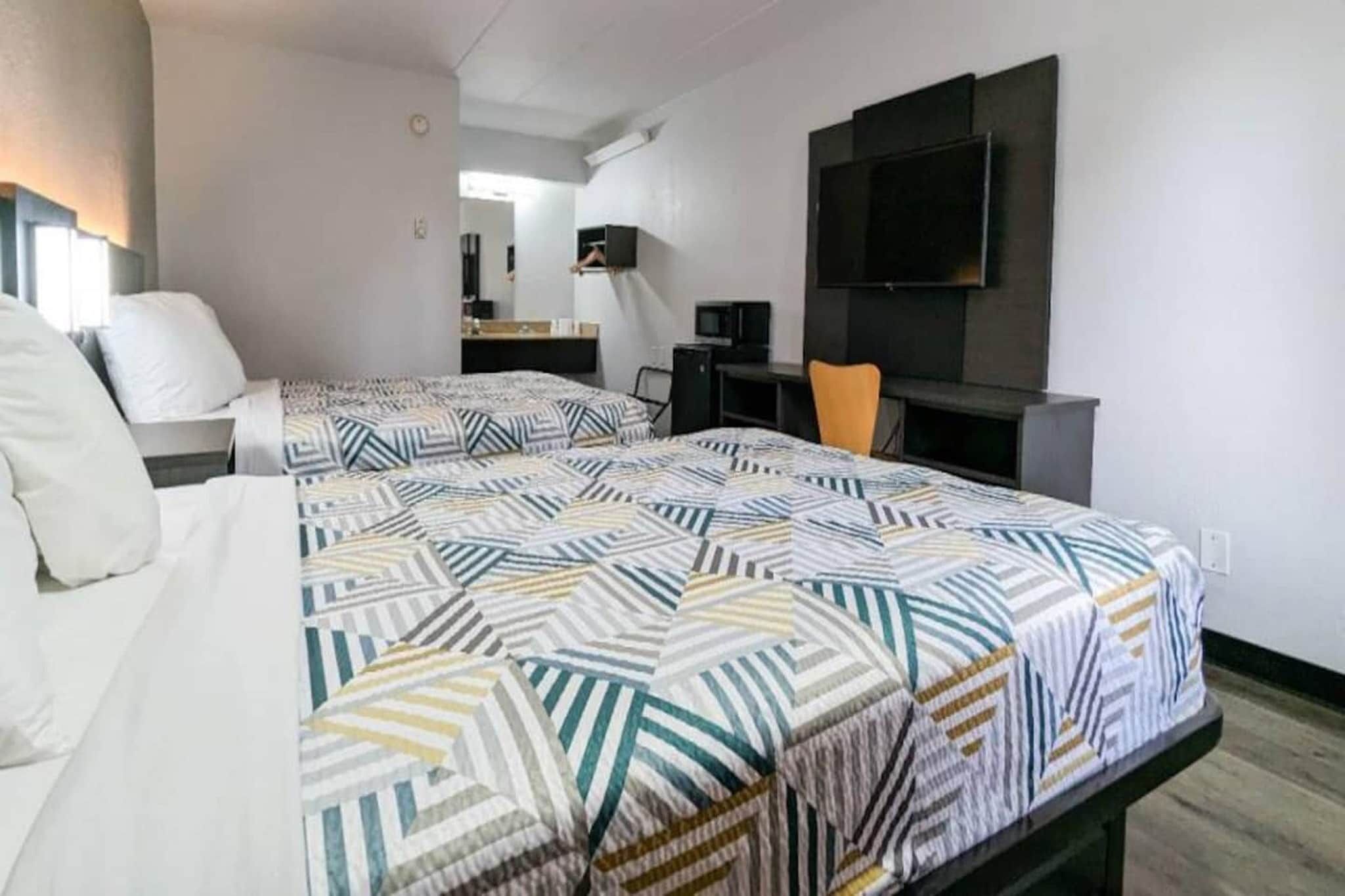 Een hotelkamer met twee bedden, een bureau, een stoel, een televisie en een spiegel.