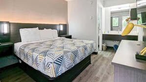 Et hotelværelse med en seng, to sengeborde, et skrivebord med lampe og et spejl.