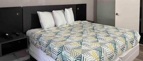 Une chambre d’hôtel standard, équipée d’un lit, d’une table de chevet et d’une armoire.