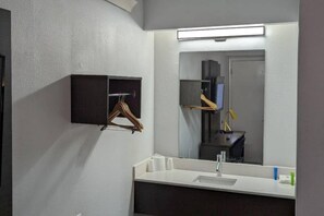 Un baño con espejo, lavamanos, toallero y un mueble pequeño.
