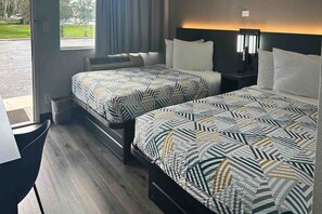Ein Hotelzimmer mit zwei Betten, einem Schreibtisch und Blick ins Freie.