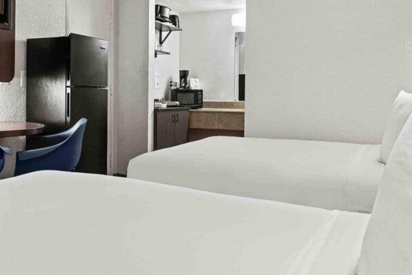 Une chambre d’hôtel avec deux lits, une petite kitchenette et un coin repas comprenant une table et des chaises.