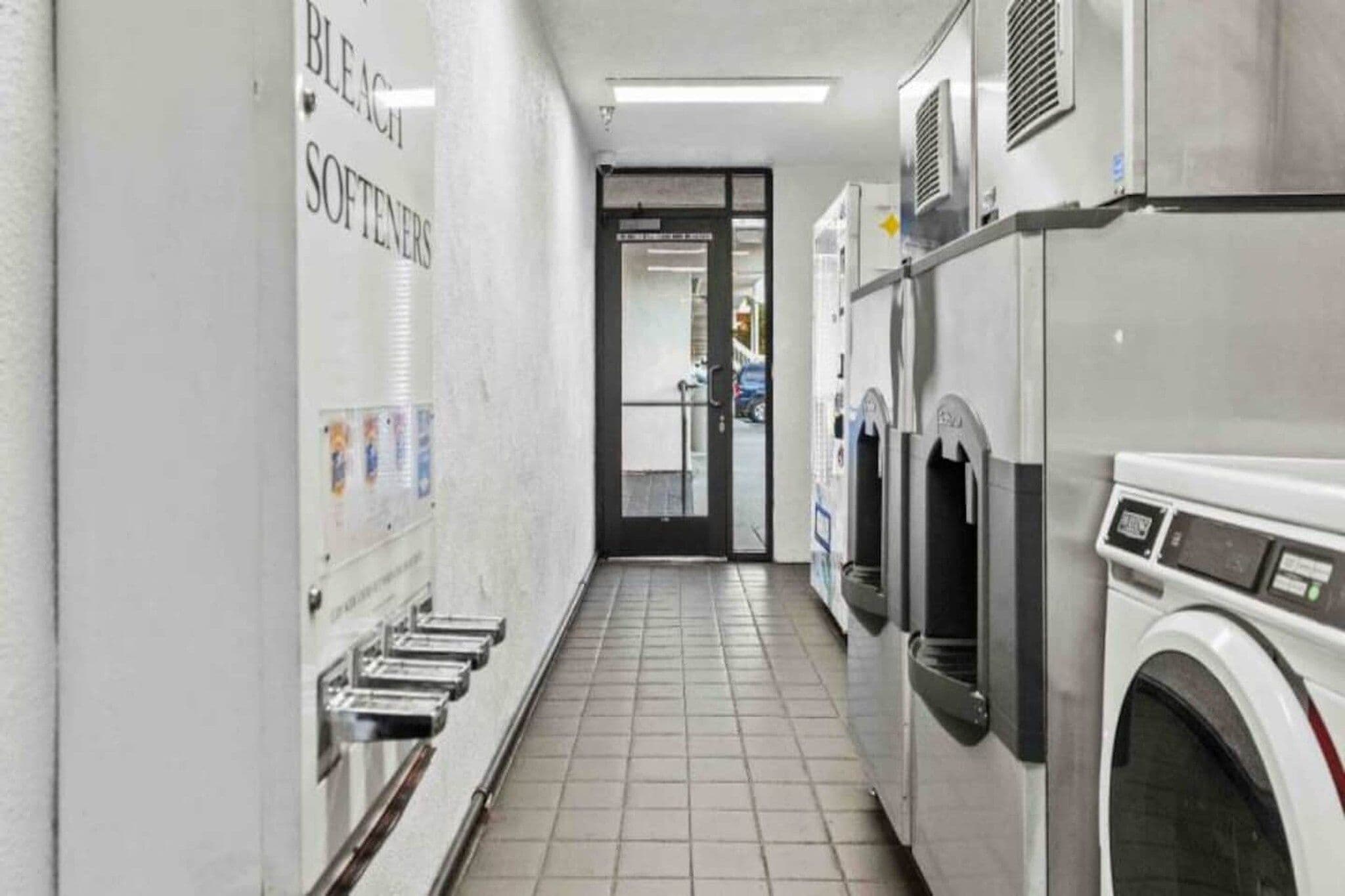 A laundry facility with multiple washing machines and a bleacher area.