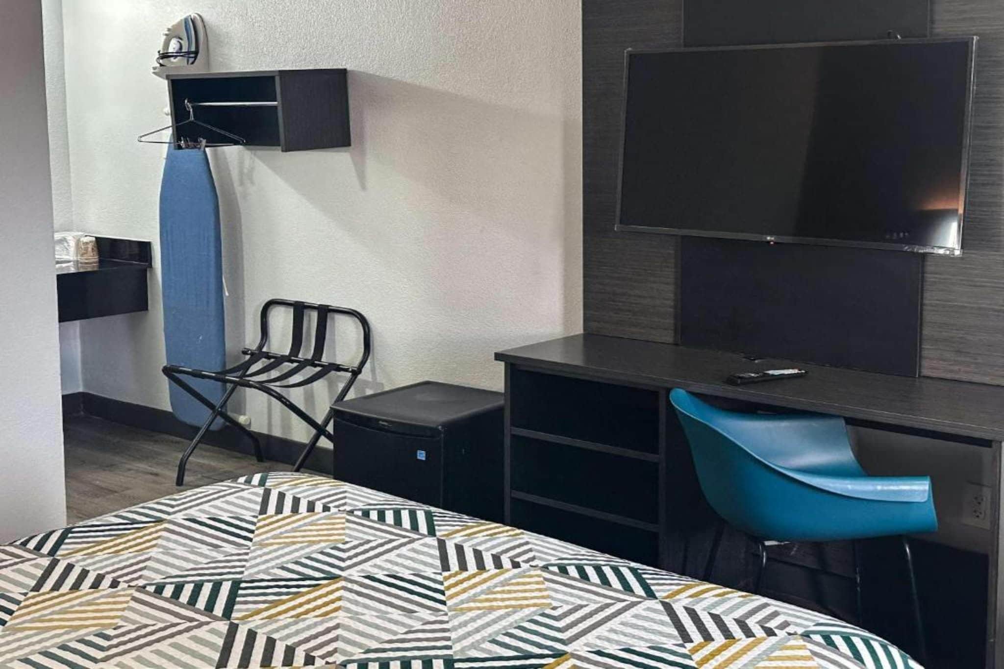 Hotellihuone, jossa on sänky, työpöytä, tuoli, televisio ja vaatekaappi.