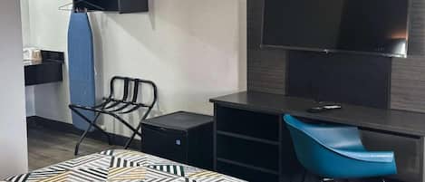 Hotellihuone, jossa on sänky, työpöytä, tuoli, televisio ja vaatekaappi.