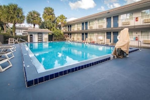 A swimming pool with lounge chairs and a covered area, surrounded by a building with multiple windows and balconies. - ADA Full Bed|Tub|Micfridge (Kissimmee)