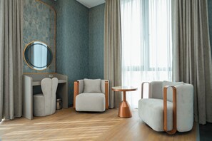 A modern room with a wooden floor, a round table, two armchairs, a desk with a mirror, and a large window with curtains. - PARK DEDEMAN KARTAL (Istanbul)
