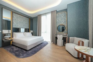 Ein modernes Hotelzimmer mit einem großen Bett, einem Schreibtisch, einem Stuhl und einem runden Tisch.