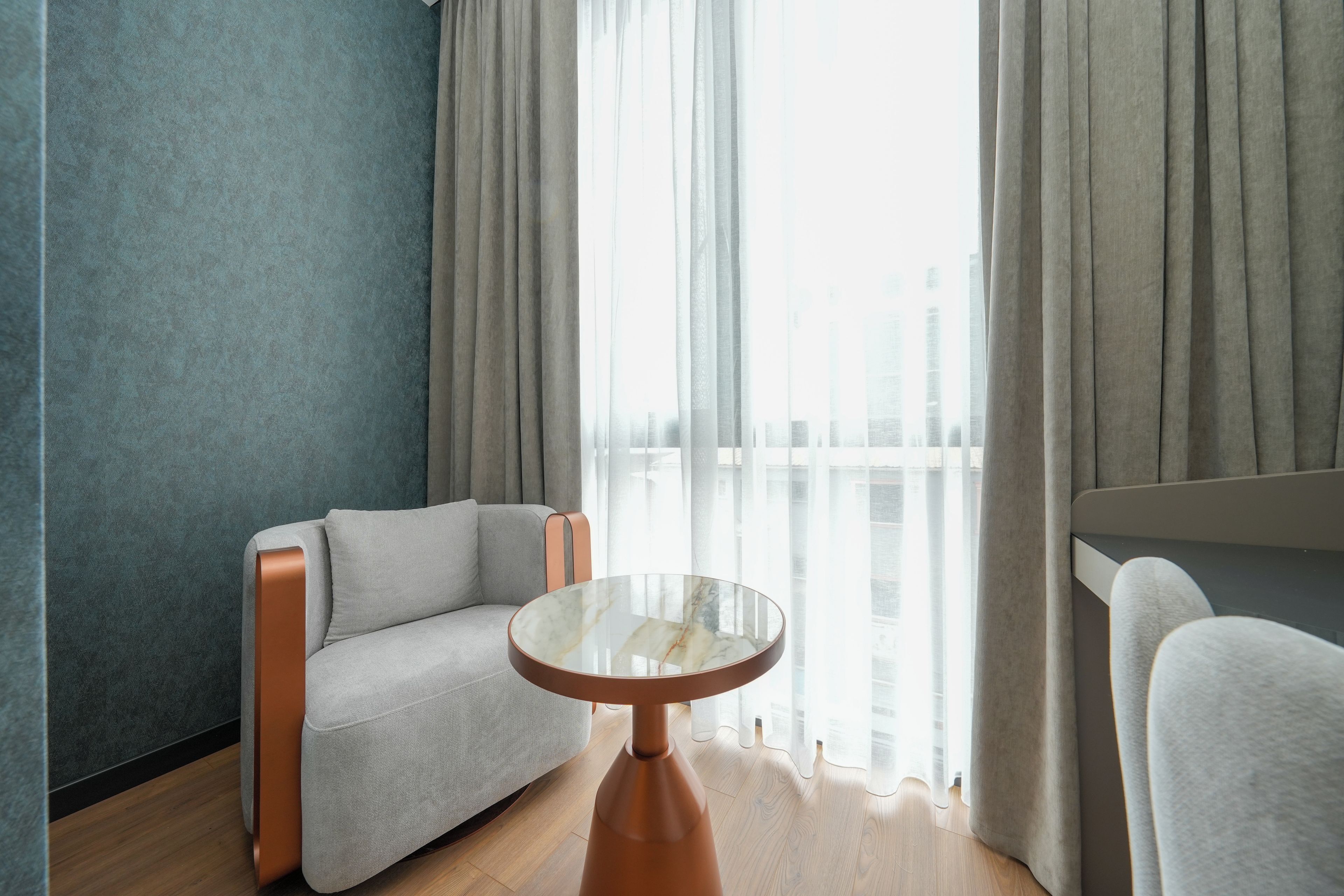 Ein modernes Zimmer mit einer Couch, einem runden Tisch und Blick durch transparente Vorhänge.