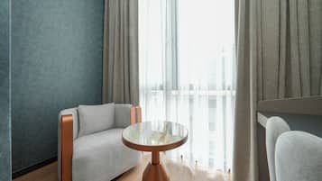 Ein modernes Zimmer mit einer Couch, einem runden Tisch und Blick durch transparente Vorhänge.