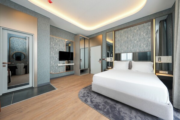 Habitación de hotel moderna con una cama grande, un televisor de pantalla plana, un espejo y un armario.
