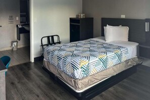 Een moderne hotelkamer met een bed, een klein bureau en een prullenbak.
