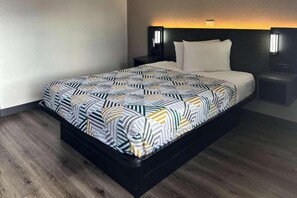 A bed with a geometric patterned bedspread, a bedside table with a lamp, and a headboard with a light fixture. - 1 Full Bed | Kissimmee (Kissimmee)