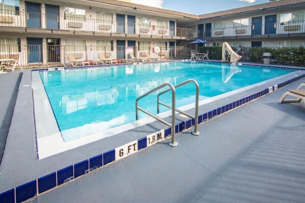 A swimming pool with a blue tiled edge, a metal ladder, and lounge chairs. - 1 Full Bed | Kissimmee (Kissimmee)
