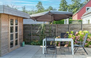 A patio area with a table and chairs, a wooden fence, and a garden with flowers. - 3 bedroom stunning home in Wemeldinge (Wemeldinge)