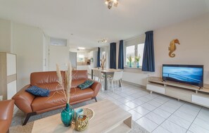A modern living room with a leather sofa, a coffee table, and a TV. - 3 bedroom stunning home in Wemeldinge (Wemeldinge)