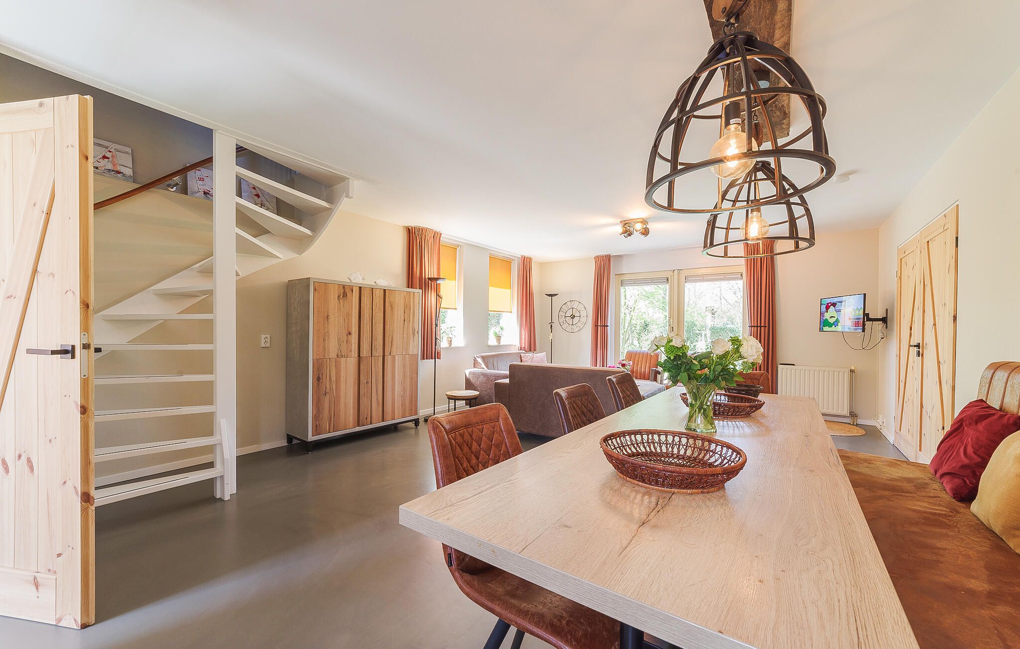 A spacious kitchen with a wooden dining table, chairs, and a hanging light fixture.