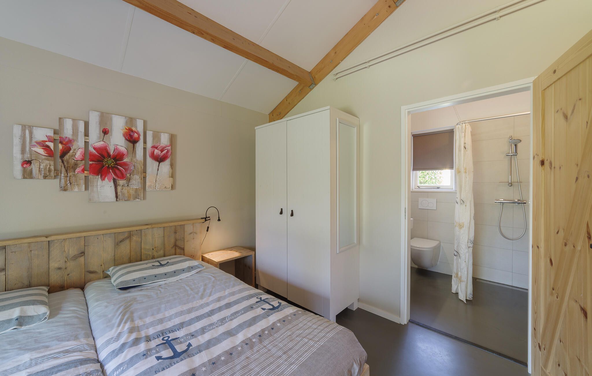 Une chambre à coucher avec un lit, une armoire, une table de chevet et un tableau au mur.