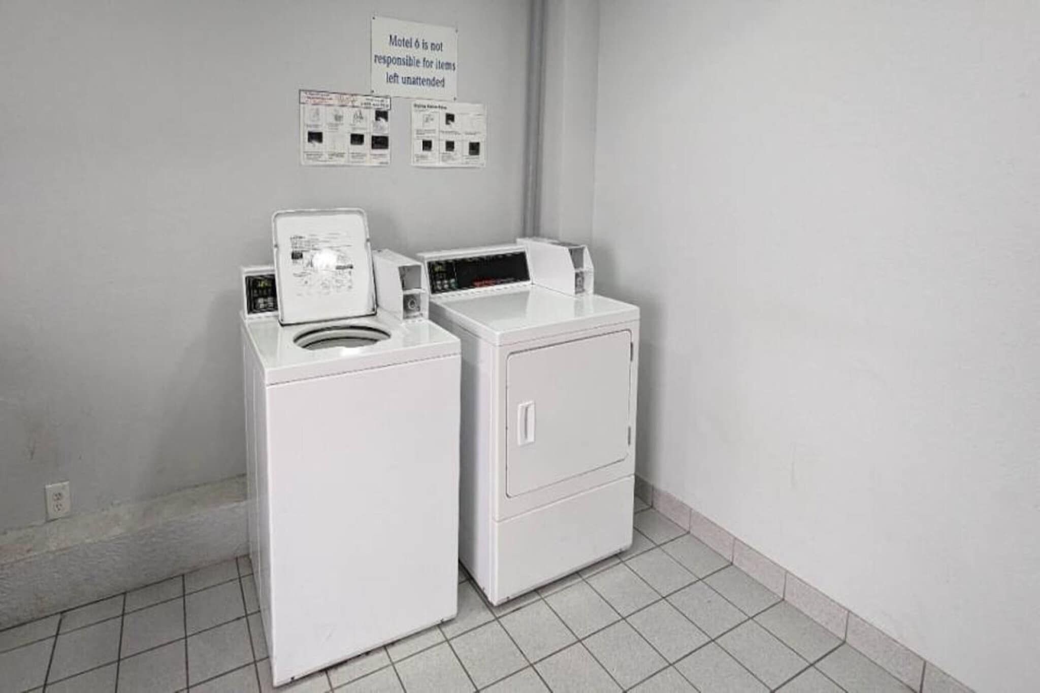 Een wasruimte met twee witte wasmachines en een bord erboven.