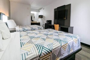 A hotel room with two beds, a desk, a chair, a TV, and a mirror.