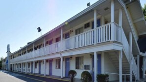 Un motel con una struttura a due piani, diverse camere con ingressi individuali e un portico coperto.