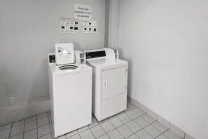 A laundry area with two washing machines and a sign indicating the motel is not responsible for unattended items.