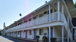 Un motel con struttura su due piani, diverse camere e un portico coperto.