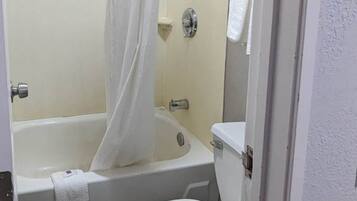 A bathroom with a bathtub, toilet, and a shower curtain.