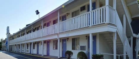 Ein Motel mit zweistöckiger Bauweise, mehreren Zimmern und einer überdachten Veranda.