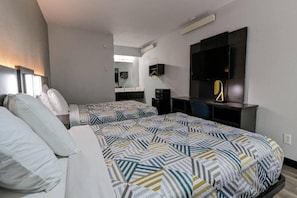 A hotel room with two beds, a TV, a desk, and a mirror.