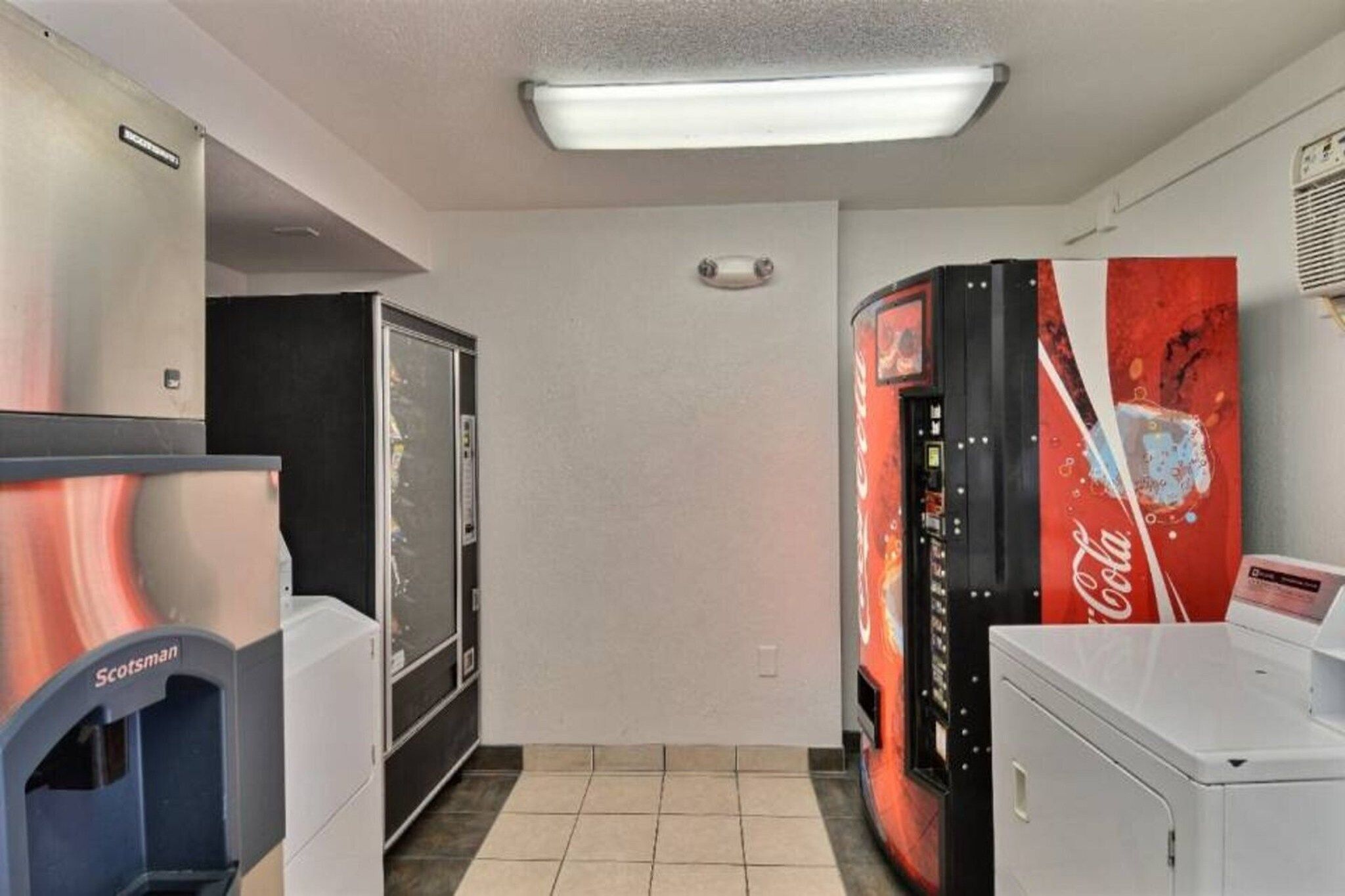 Een kamer met een automaat, een koelkast en een Coca-Cola koelkast.