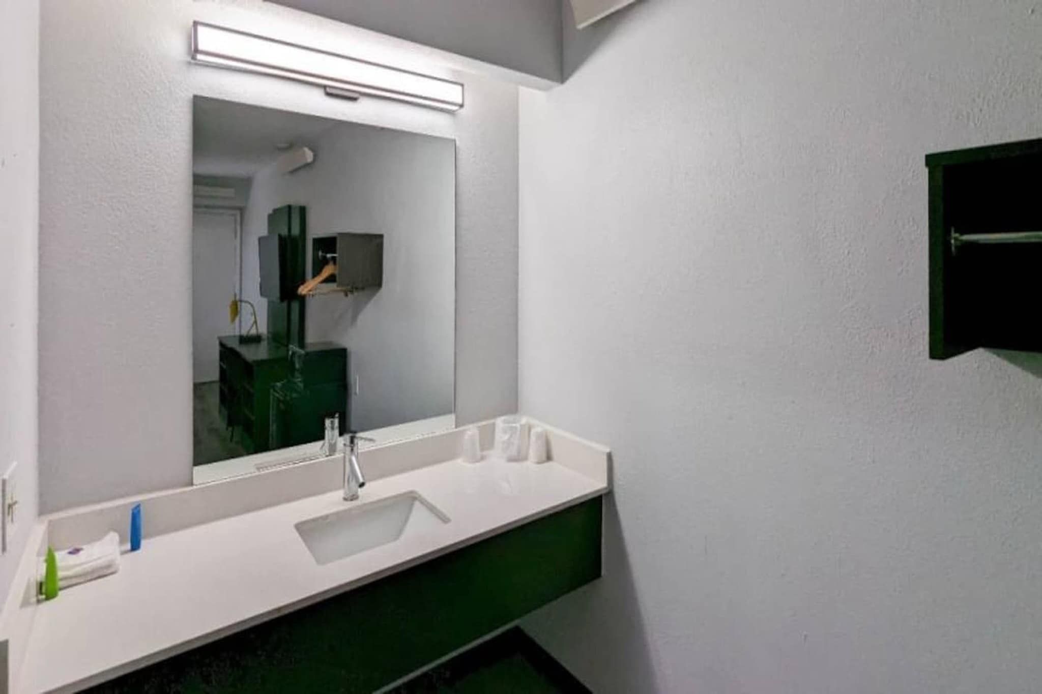 A modern bathroom with a white sink, a mirror, and a green cabinet.