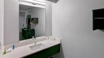 Une salle de bain moderne avec un lavabo blanc, un miroir et un meuble vert.