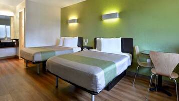 A hotel room with two beds, a desk, and a chair.