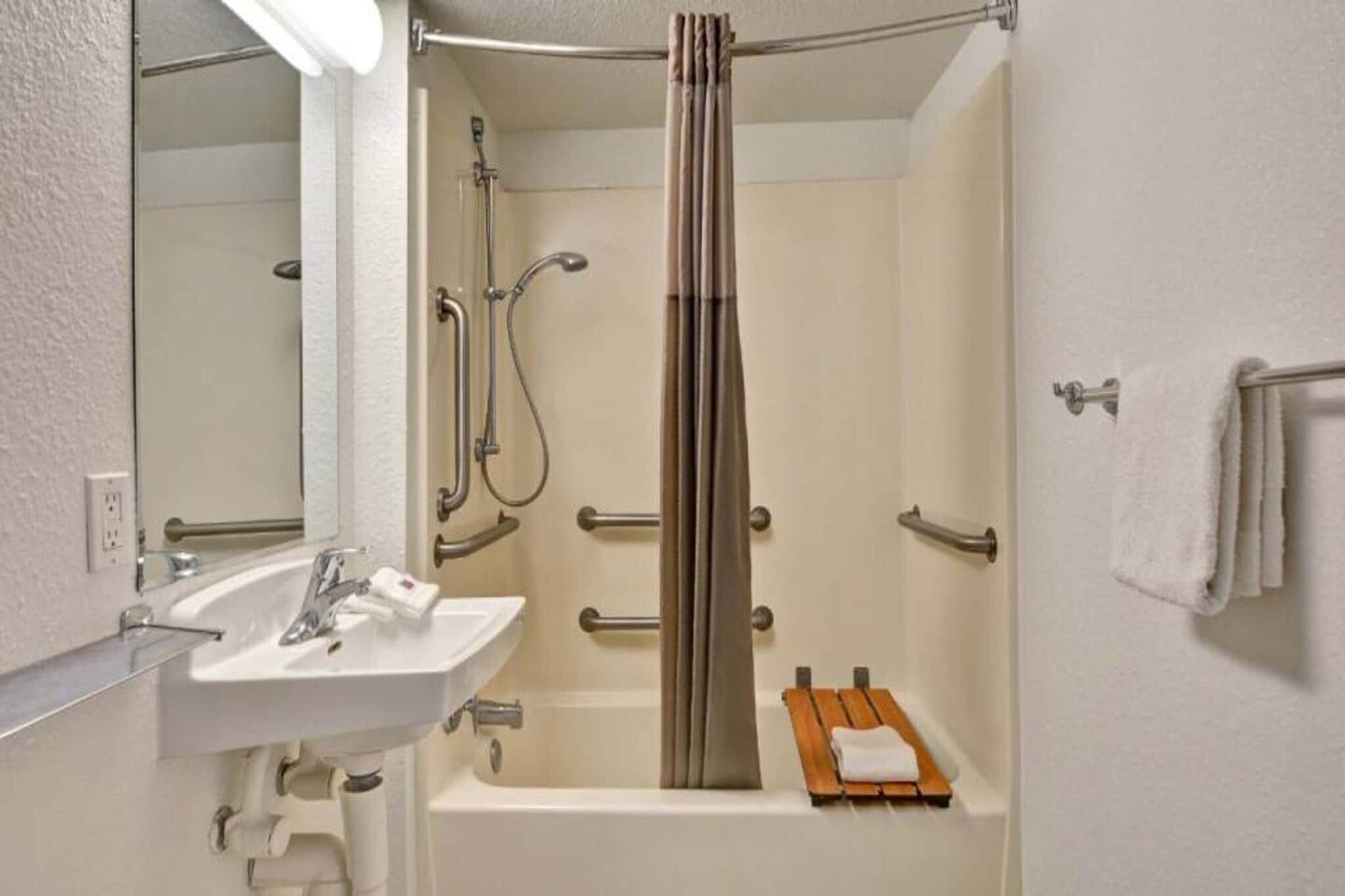 A bathroom with a white sink, a bathtub, a shower with a curtain, and a towel rack.