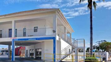 A building with a 'welcome' sign, a covered entrance, and a staircase leading to an upper level.