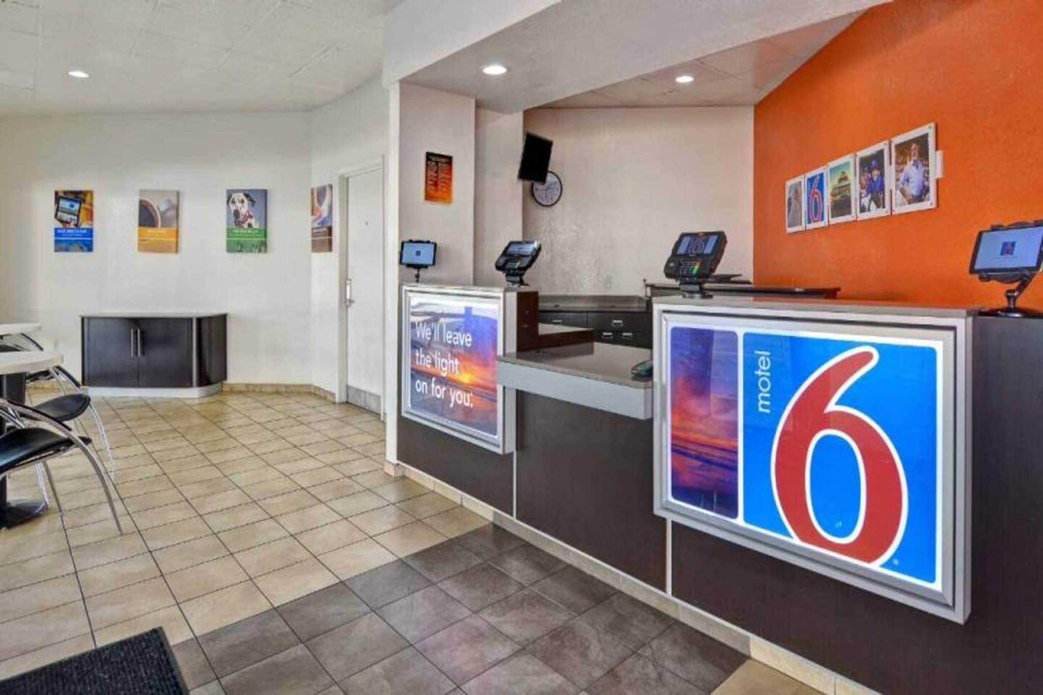 A hotel reception area with a counter, a digital display, and a sign indicating the hotel name 'motel 6'.