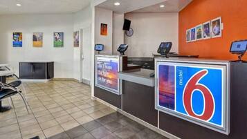 A hotel reception area with a counter, a digital display, and a sign indicating the hotel name 'motel 6'.