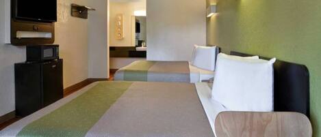 A hotel room with two beds, a television, a microwave, and a small kitchenette.