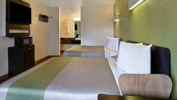 Une chambre d’hôtel avec deux lits, une télévision, un four à micro-ondes et une petite kitchenette.