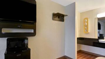 A modern kitchen with a microwave, a coffee machine, and a flat-screen TV mounted on the wall.